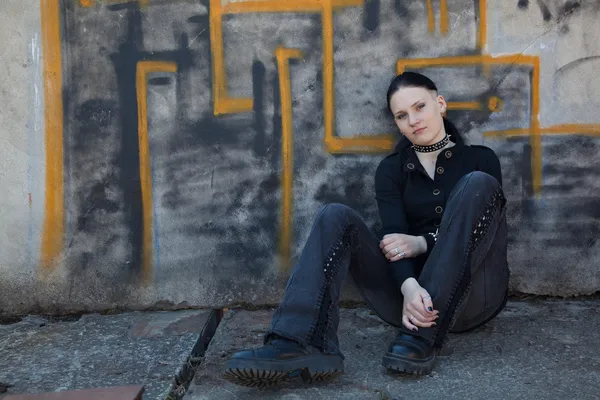 Jovem sentada na frente da parede de grafite — Fotografia de Stock