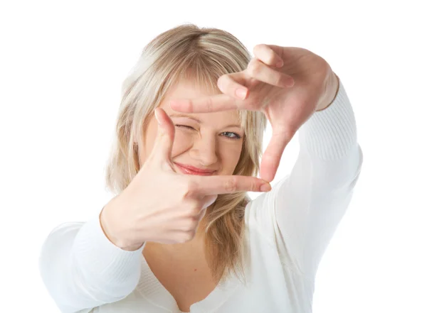 Mujer rubia joven mirando a través de un marco hecho por sus dedos —  Fotos de Stock