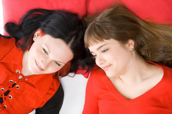 Dos chicas tumbadas sobre una almohada roja —  Fotos de Stock