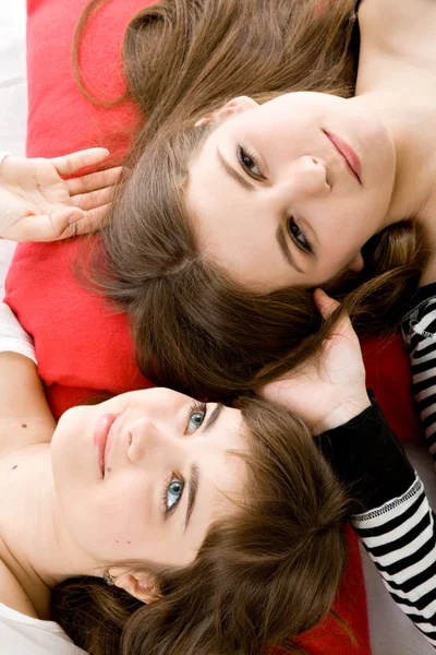Две девушки лежат на красной подушке — стоковое фото