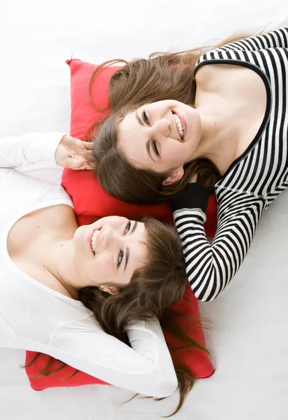 Two girls lying on red pillow — Stock Photo, Image