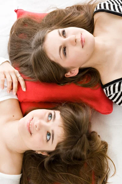 Две девушки лежат на красной подушке — стоковое фото