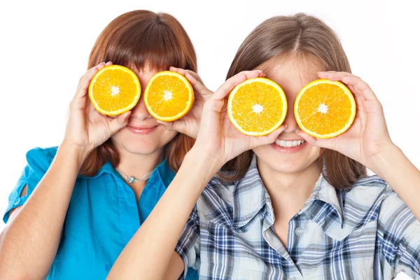 Two girls are looking through oranges — Stock Photo, Image
