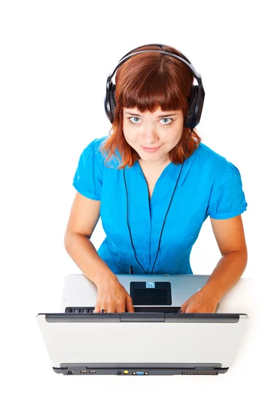 红头发的青年女孩在听音乐的笔记本电脑的耳机 — 图库照片