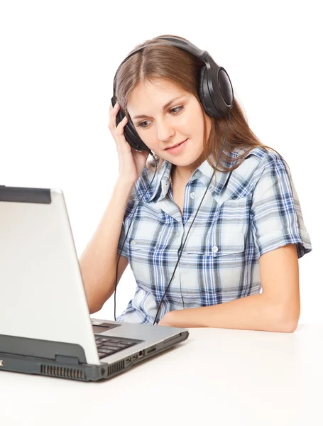 Una chica está escuchando la música y mirando un portátil — Foto de Stock