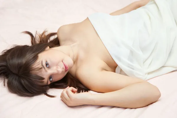 Νεαρή κοπέλα ξαπλωμένη σε ένα κρεβάτι — Φωτογραφία Αρχείου