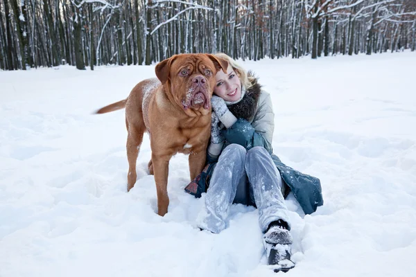 Красива жінка сидить біля свого собаки в зимовому парку — стокове фото