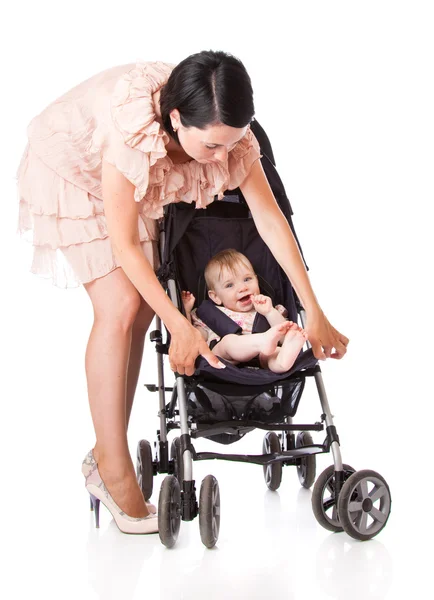 En ung kvinna står nära sitt barn i barnvagn — Stockfoto