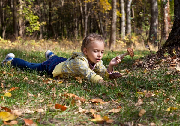 一个微笑着的女孩躺在森林的草地上 — 图库照片