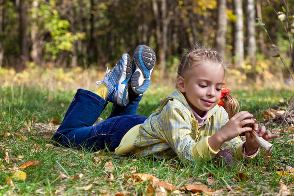 一个微笑着的女孩躺在森林的草地上 — 图库照片