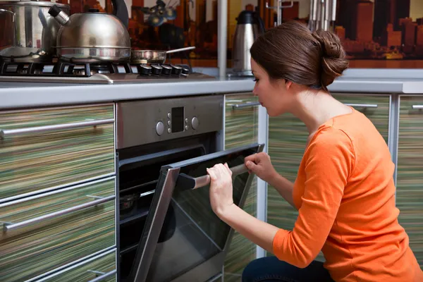 Una joven está cocinando en la estufa. Imagen De Stock