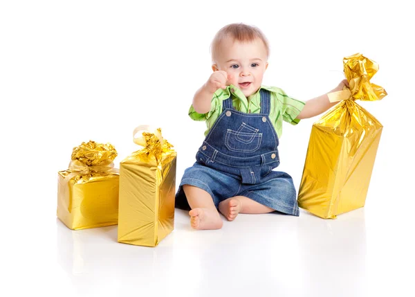 Menino pequeno com três presentes em embalagem brilhante — Fotografia de Stock