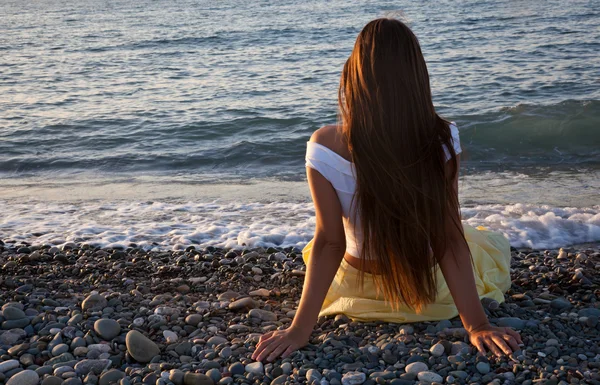 Uma mulher está sentada numa praia — Fotografia de Stock