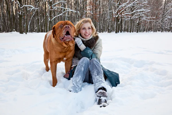 Kobieta siedzi na śniegu z psem — Zdjęcie stockowe