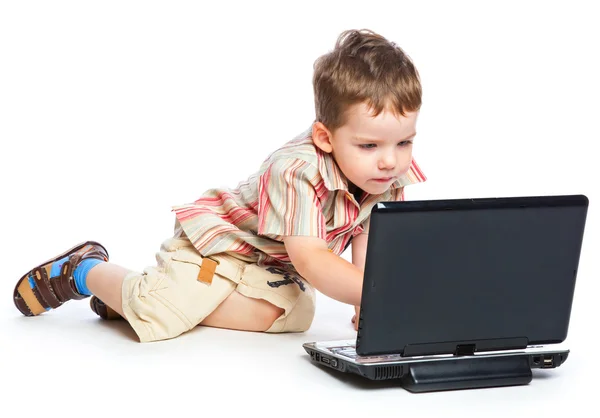 Een schattige jongen typt op een laptop — Stockfoto
