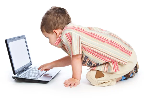Een schattige jongen typt op een laptop — Stockfoto