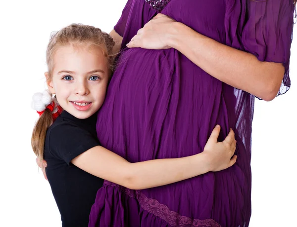 Una chica sonriente está escuchando el abdomen de su madre —  Fotos de Stock