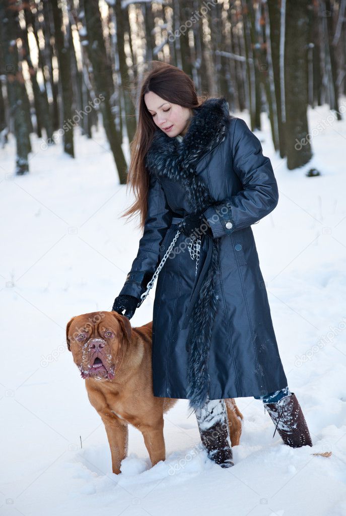 A beautiful woman is walking in the park with her dog