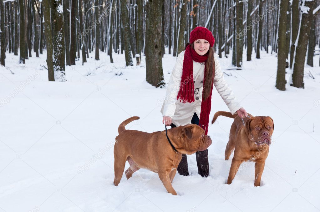 A beautiful woman is walking in the park with her dogs