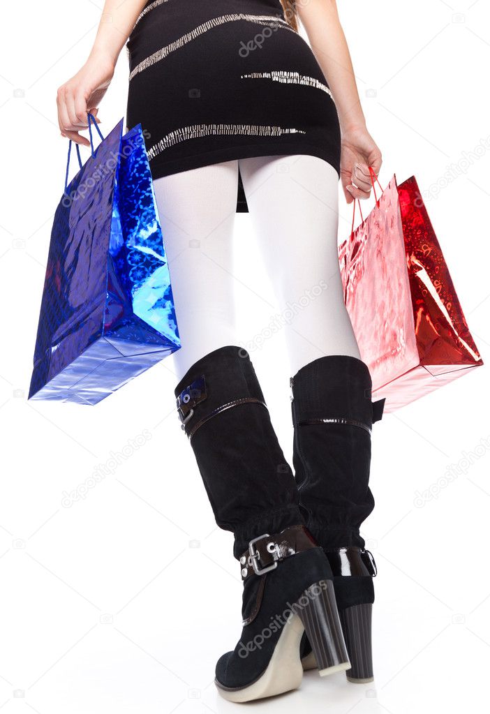 A woman in high boots keeps bright bags. isolated on a white background