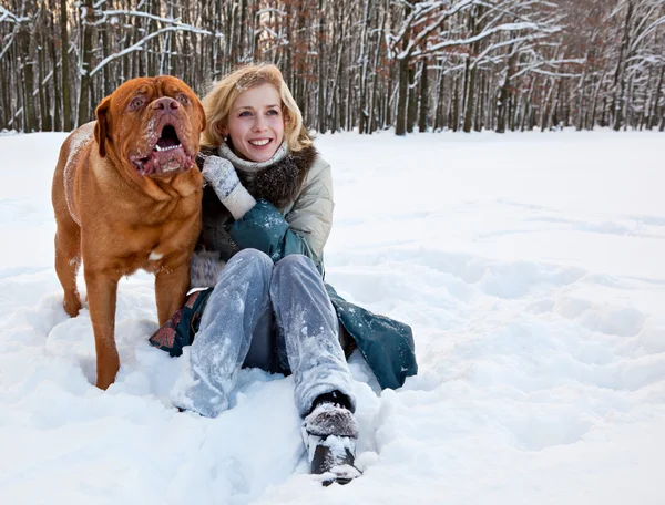 Uma mulher está sentada na neve com seu cachorro — Fotografia de Stock