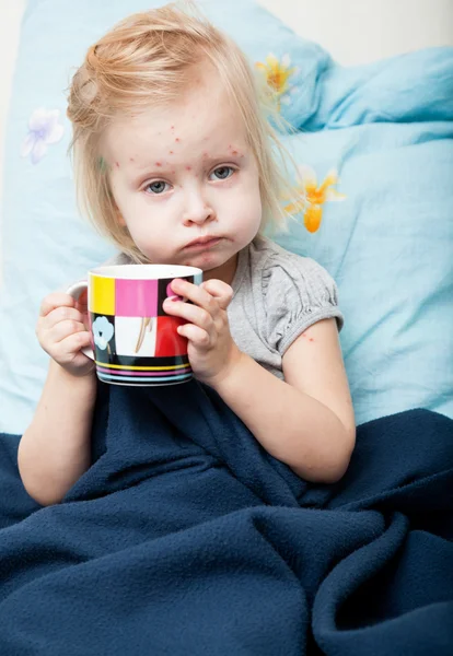 Uma menina doente está sentada perto da cama — Fotografia de Stock