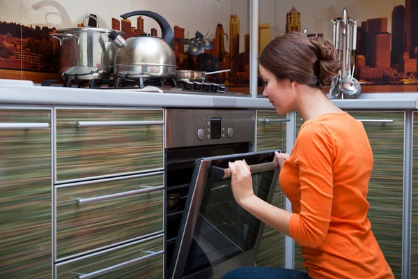A young woman is cooking in the stove — Stock Photo, Image