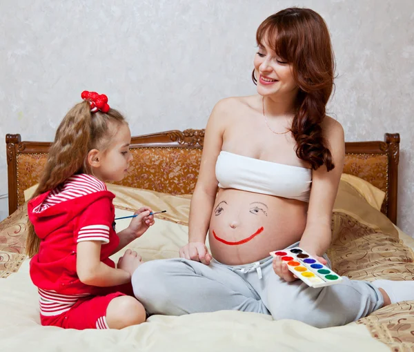 Uma filha está pintando na barriga de sua mãe — Fotografia de Stock