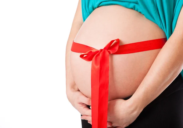 Hamile bir kadının karnı üzerinde kırmızı yay — Stok fotoğraf