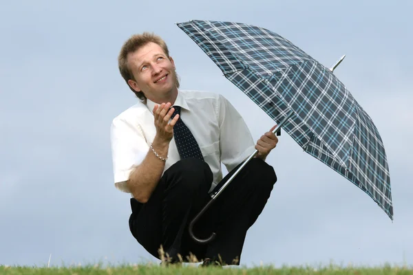 Человек с зонтиком смотрит в небо — стоковое фото