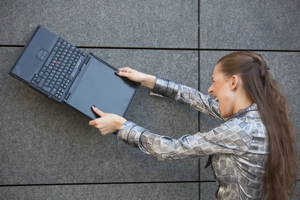 Woman crushing laptop against wall — Stock Photo, Image