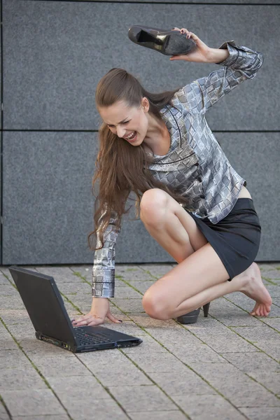 Frau schlägt Laptop mit Schuh — Stockfoto