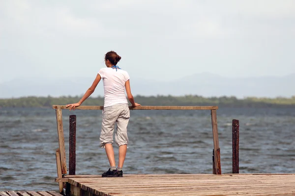 Kobieta stojąc na drewnianym molo — Zdjęcie stockowe