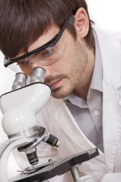 Исследователь смотрит в микроскоп Стоковая Картинка