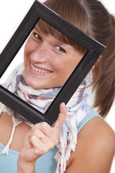Mujer mirando a través de marco de fotos — Foto de Stock