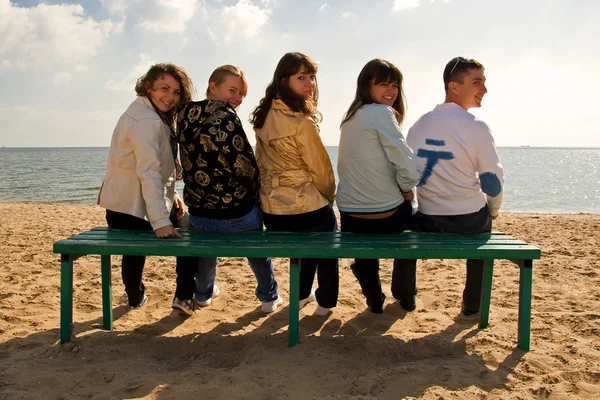 ベンチに笑みを浮かべて若者のグループ — ストック写真