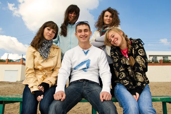 Group of smiling young on a bench — Stock Photo, Image