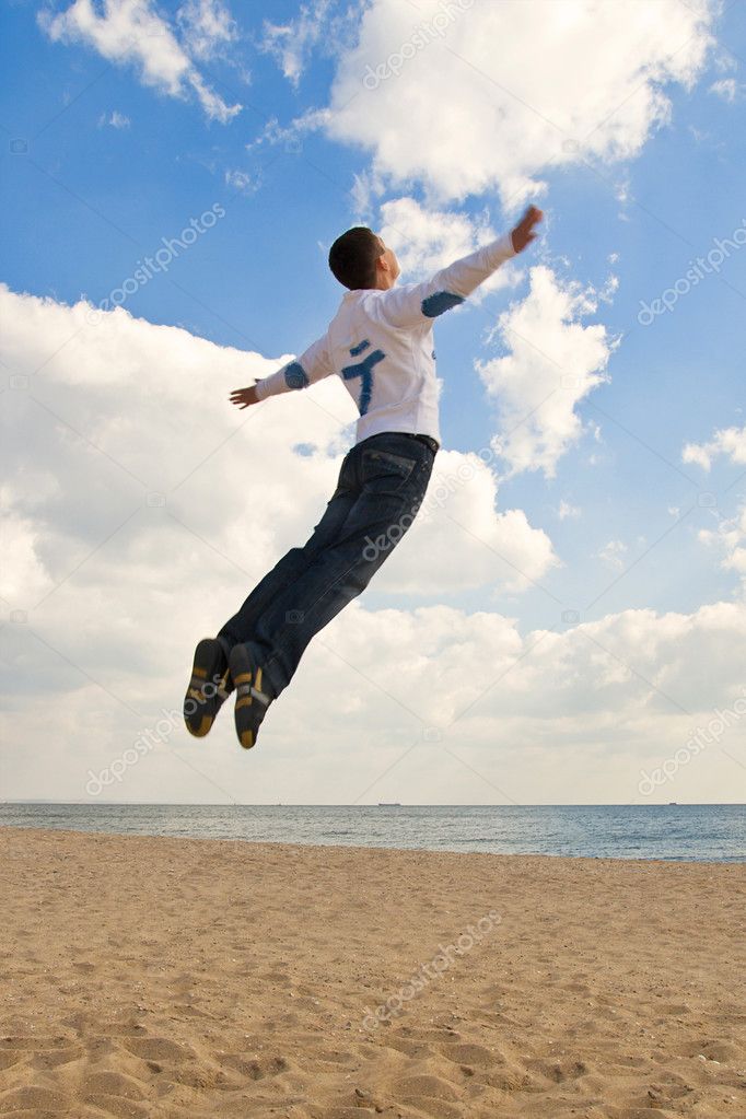 Guy jumping into the sky at the beach