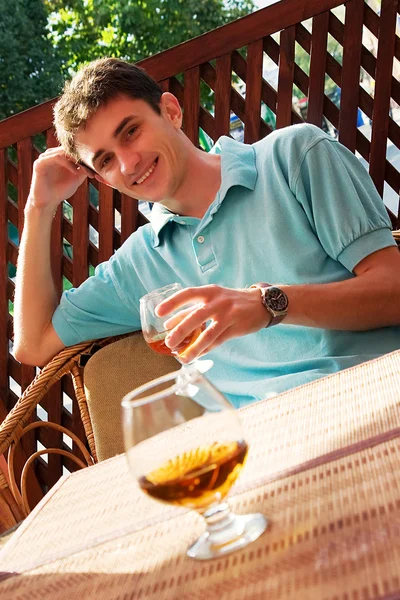 stock image Young smiling guy sits in a summer cafe