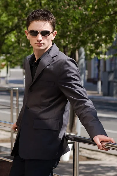 Young businessman in sunglasses leans on handrails — Stock Photo, Image
