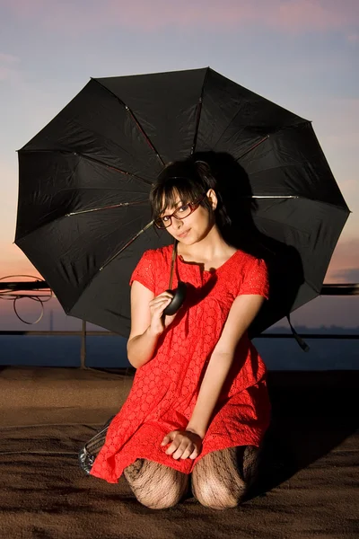 Attractive young lady sitting with an umbrella on the rooftop — Stock Photo, Image