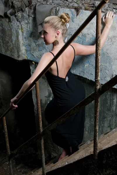Beautiful woman standing on the grungy stairs — Stock Photo, Image