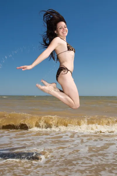 Smiling chick in swimsuit jumping at the seaside — Stock Photo, Image