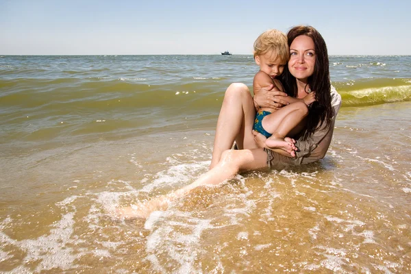 Νεαρή μητέρα κρατώντας το γιο της στα χέρια στην παραλία — Φωτογραφία Αρχείου