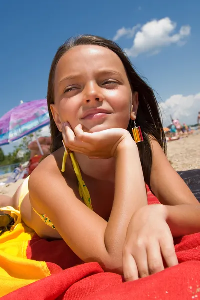 Küçük kız plajda güneşlenirken — Stok fotoğraf