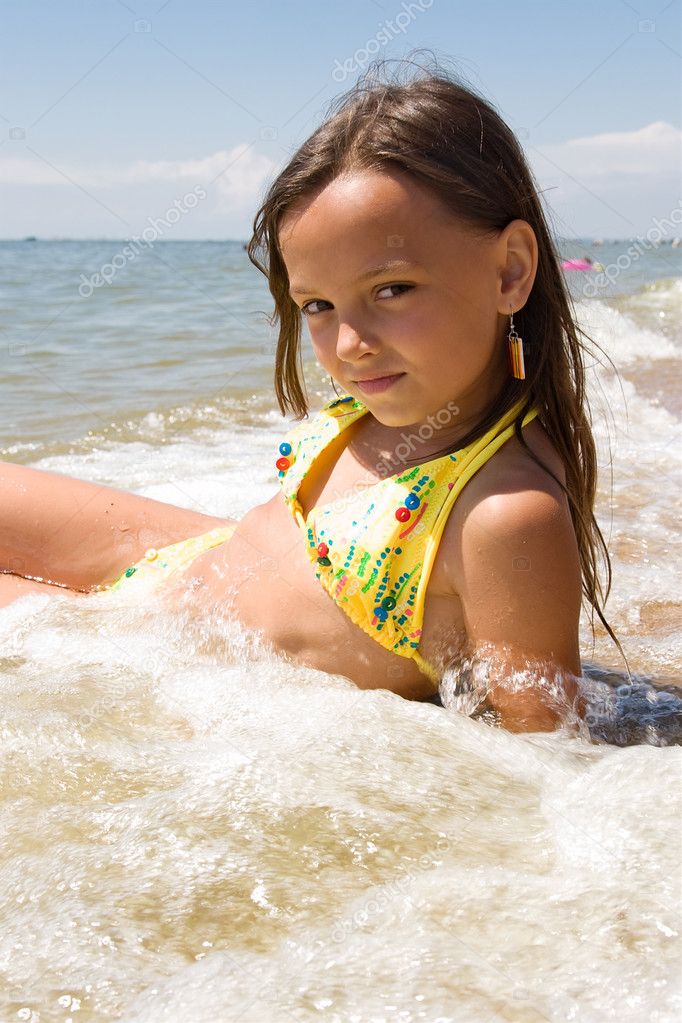 Little girl in water splashes of a sea