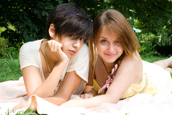 Twee meisjes opleggen aan de coverlet op groen gras — Stockfoto