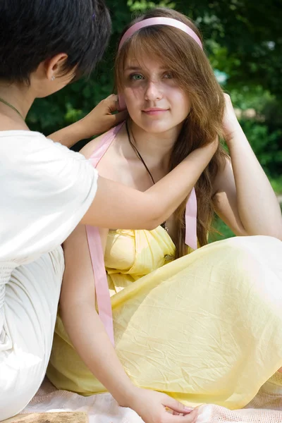 Chica trenzando su pelo amigos al aire libre — Foto de Stock