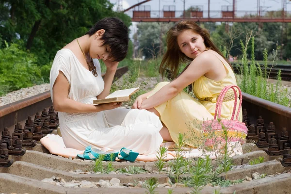 Girls sitting on the railroad carelessly — Stock Photo, Image