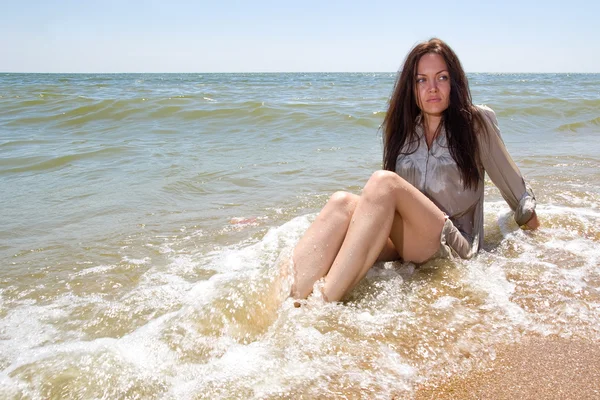 Νεαρή κοπέλα κάθεται στο νερό μια θάλασσα — Φωτογραφία Αρχείου